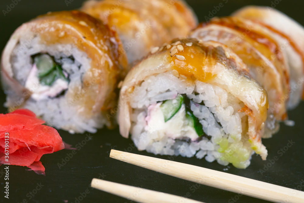 Sushi with eel and hayash wakamei salad lie on a black board made of stone slate Sushi with eel and hayash wakamei salad lie on a black board made of stone slate