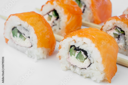 Sushi philadelphia with salmon lie on a white background with chopsticks