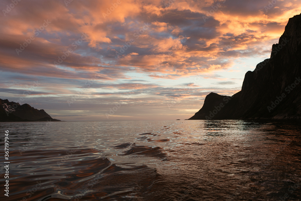 Scenic clouds during amazing sunset in the norwegian fjord. Evening light on the sea with mountains in background. View from the boat. Senja island, north Norway. Scenic clouds during amazing sunset in the norwegian fjord. Evening light on the sea with mountains in background. View from the boat. Senja island, north Norway.