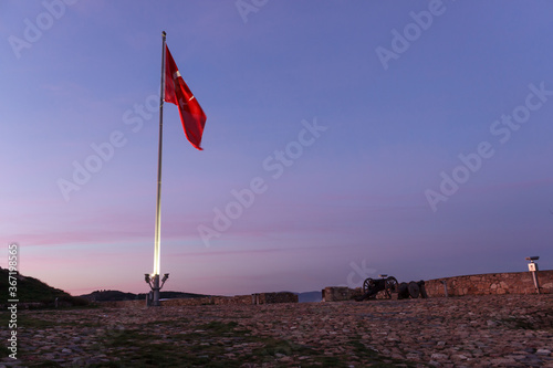 Turkish flag with pole waving on old historical castle, landscape with purple sky