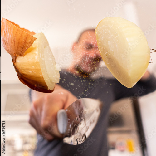 Young man cutting an onion in the air - Close up male hand holding sharp knife preparing a onion salad - People lifestyle and healthy exotic food concept - Focus on male hand photo