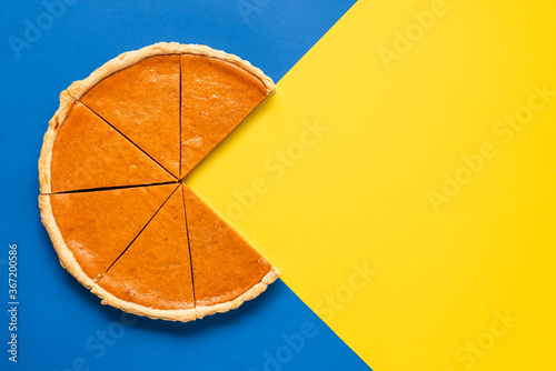 Pumpkin pie home-baked, above view. Sliced pie isolated on a colorful background