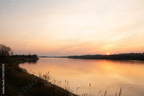 Beautiful sunset on the banks of a large river © Serhii Prystupa