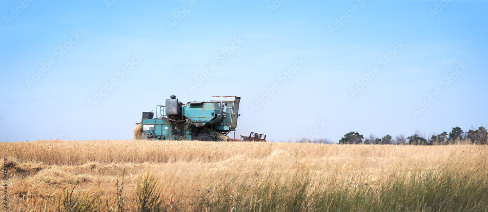 Retro harvester working in the field against the background of the sunset sky. Harvest, landscape of the countryside. Art processing. Concept of agriculture and natural beauty.