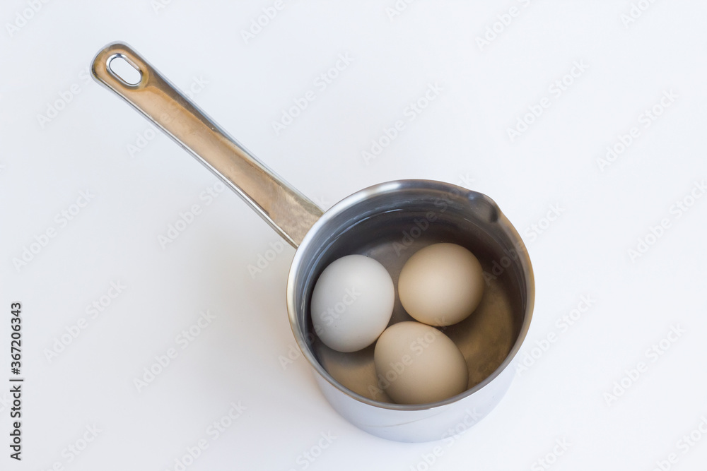 Boiled eggs in stainless mini pan on white background with copy space,top view. Boiled eggs in stainless mini pan on white background with copy space,top view.