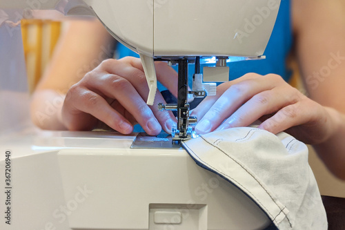 Woman using sewing machine to sew a hand-made face mask at home