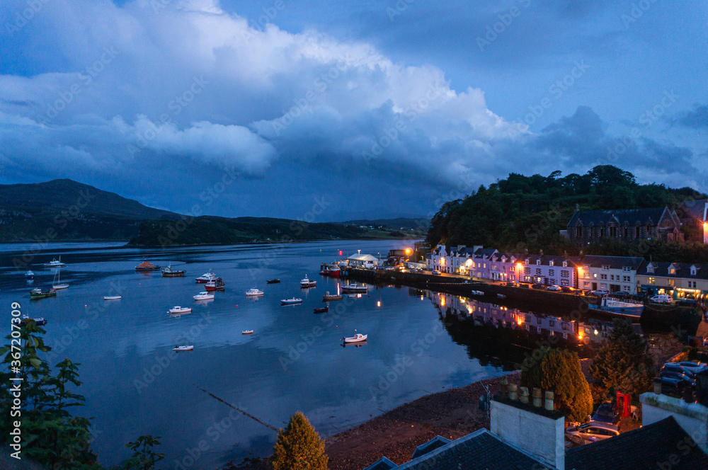 beautiful little port city at night, the harbor of Portree at night, at the Isle of Skye. Little fishing boats and reflections on the water.