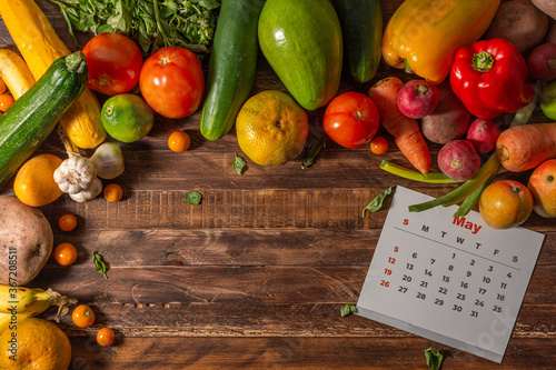 Fototapeta Naklejka Na Ścianę i Meble -  Frame of assorted fresh fruits and vegetables and calendar in english language on wooden background