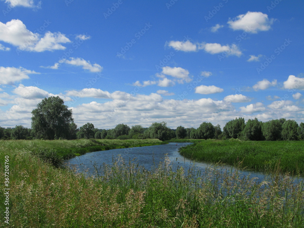 Rural landscape with Motlawa river in Olszynka district at the far end of Gdansk - blue sky with some clouds, river and green grass