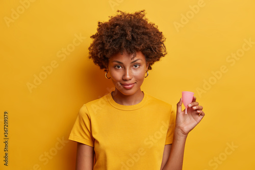 Confident woman advertises silicone reusable menstrual cup for women during periods as alternative to tampons and sanitary napkins, tells how to use feminine hygiene product. Best internal protection photo