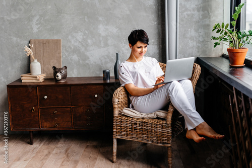 Pretty lady working on her laptop while sitting in an armchair