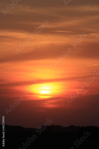 Colorful Sunset with tree Silhouettes and clouds out in the country in Kansas. © Stockphotoman