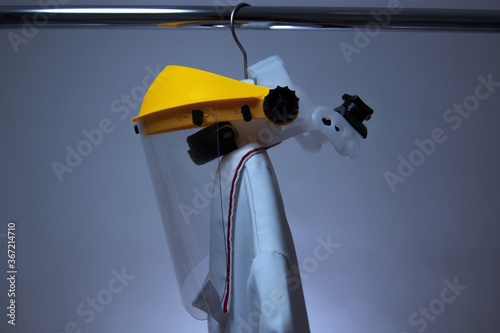Nurse overall and face shield hanging on a rail during Coronavirus outbreak or Covid-19