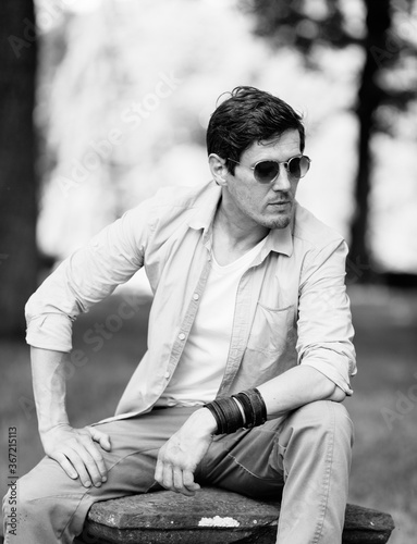 Handsome male wearing sunglasses sitting in the park