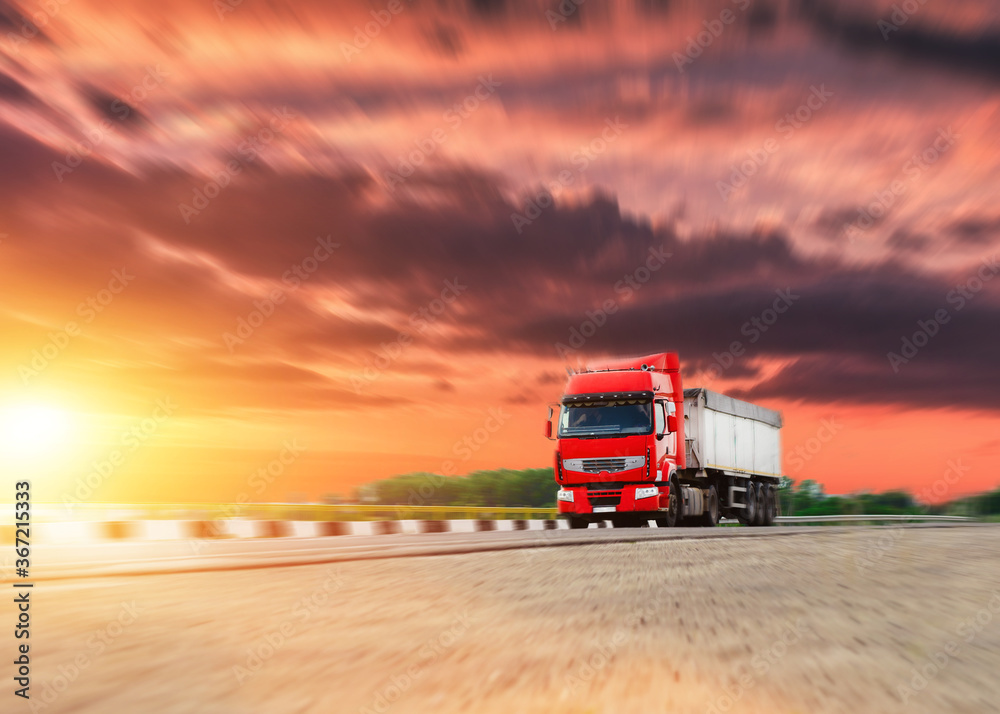 European Truck with container driving on the asphalt road in rural landscape at dramatic sunset.
European Truck with container driving on the asphalt road in rural landscape at dramatic sunset.