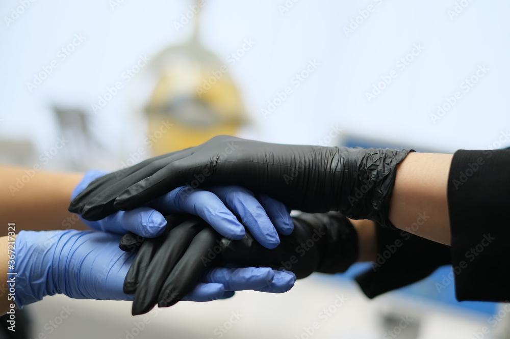 hands in Black and blue latex gloves on dental ofice background