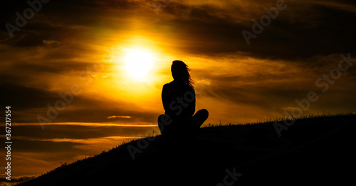  woman meditating on a sunset background