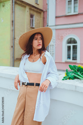 Obraz na płótnie Young happy beautiful girl is walking in a shirt and pants with a bouquet of flowers of sunflowers on a city street w salonie
