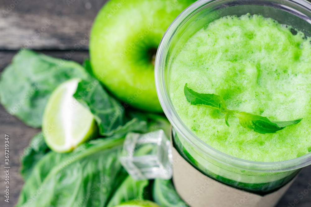 Green apple smoothie in glass and kale leaves on wooden table Green apple smoothie in glass and kale leaves on wooden table