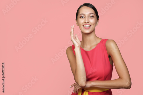 Happy woman in a pink dress on a pink background. Bright studio photo