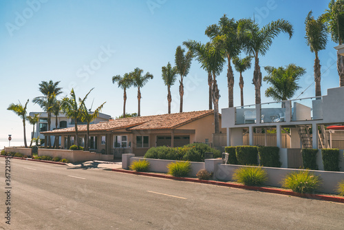 Fototapeta Naklejka Na Ścianę i Meble -  Street view, and beautiful houses with palm trees and nicely landscaped front the yard in small beach town in California.