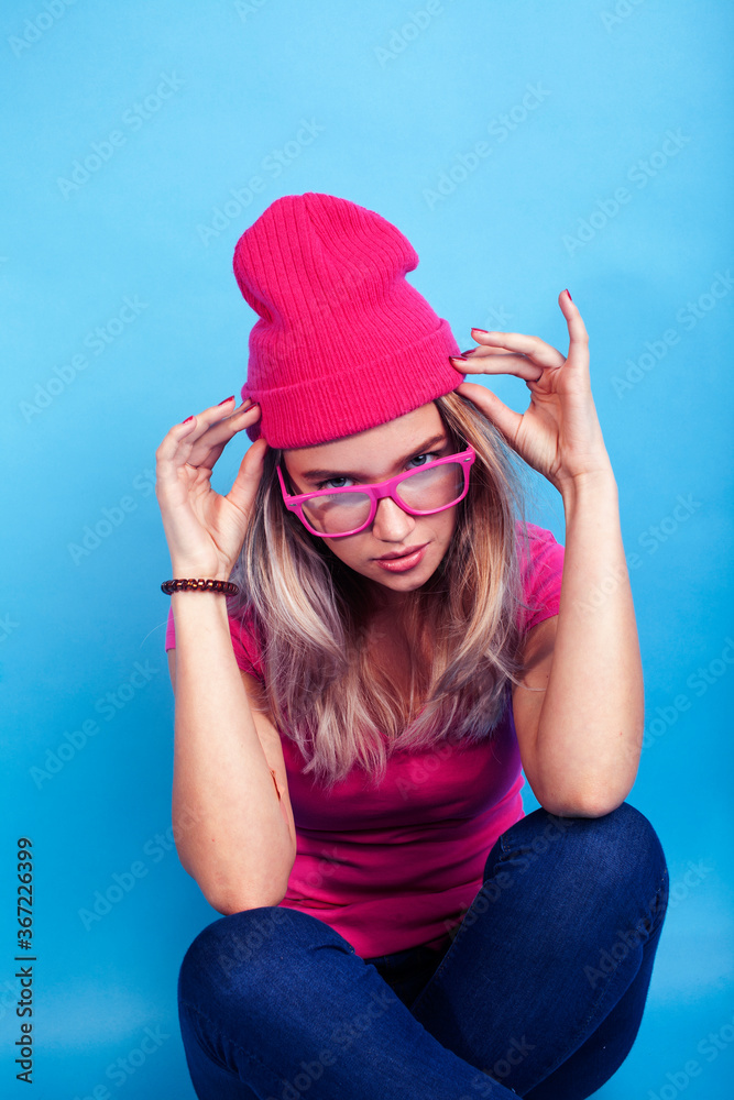 young pretty teenage modern hipster girl posing emotional happy on blue background, wearing pink hat and glasses, lifestyle people concept young pretty teenage modern hipster girl posing emotional happy on blue background, wearing pink hat and glasses, lifestyle people concept
