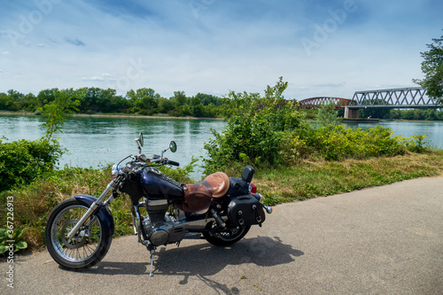 Motorrad steht einsam am Rhein, Im Hintergrund die alte Brücke Wintersdorf