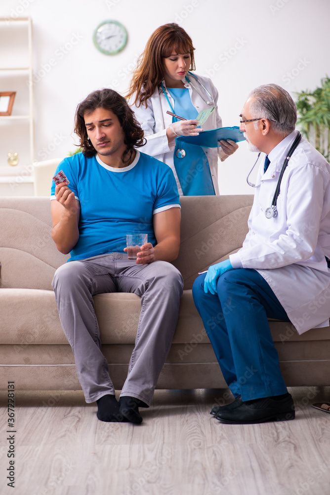 Two doctors visiting sick young man at home Two doctors visiting sick young man at home