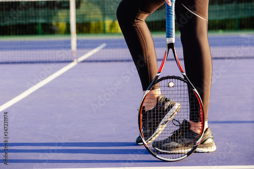 Legs of female tennis player racket. © Katsiaryna