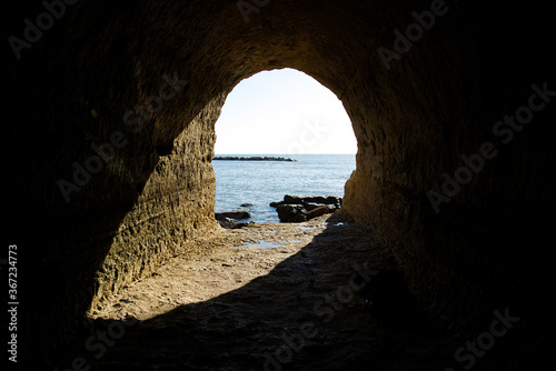 Canvastavla Sunshine into the rock cave in the cliff on anzio beach, Rome in Italy