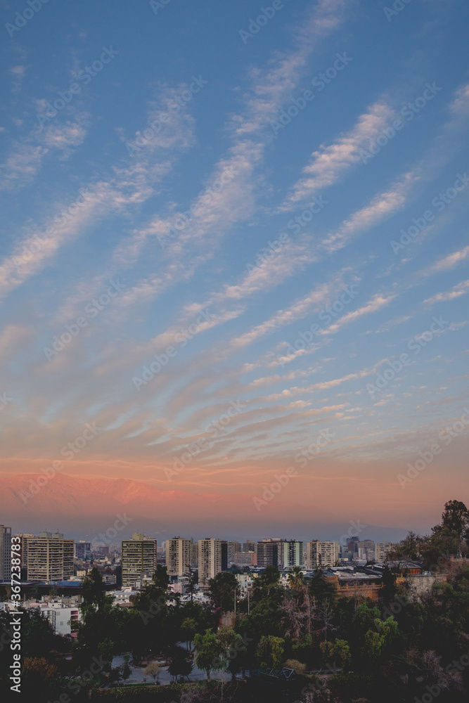 Beautiful pattern of clouds and sunset sky over Santiago downtown and Los Andes mountains with golden sunlight, Santiago de Chile