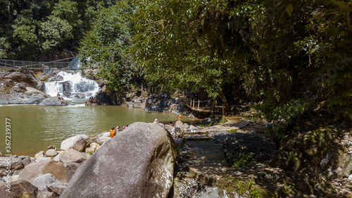 TERENGGANU, MALAYSIA - JULY 23, 2020: Tourist enjoying the beautiful of Lasir waterfall, Kenyir Lake, Terengganu. Lasir waterfall or Air Terjun Lasir. photo