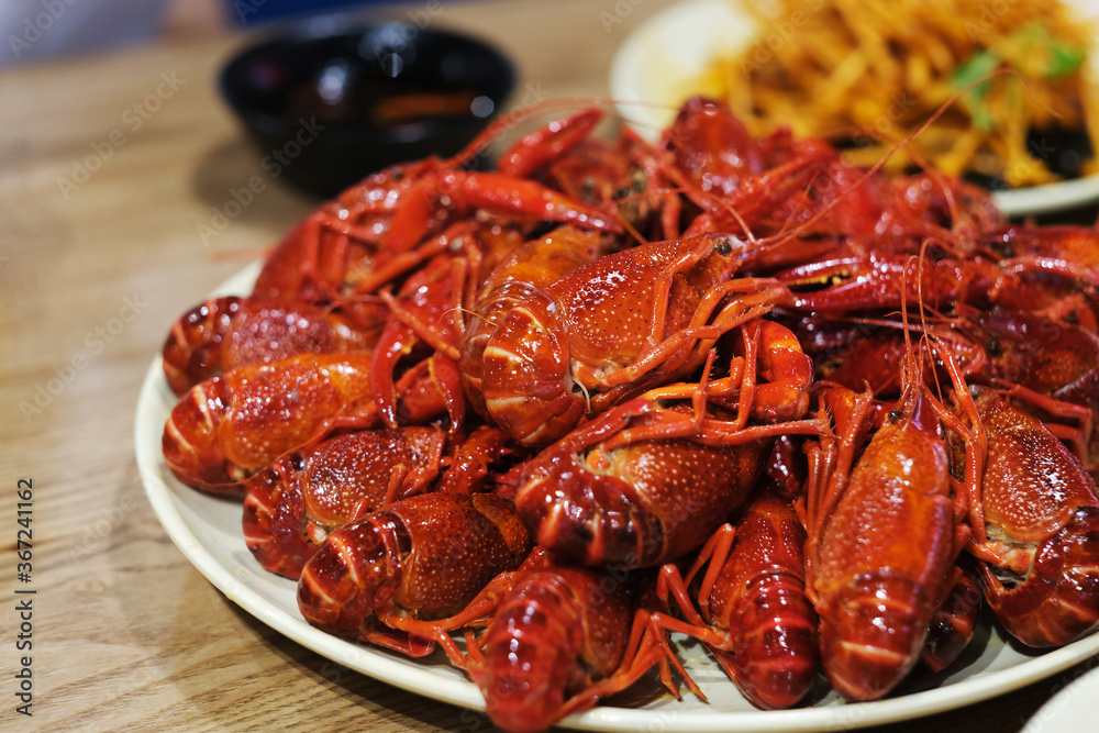 close up many steamed spicy Red Swamp Crayfish in plate on table. blur background. popular food in China