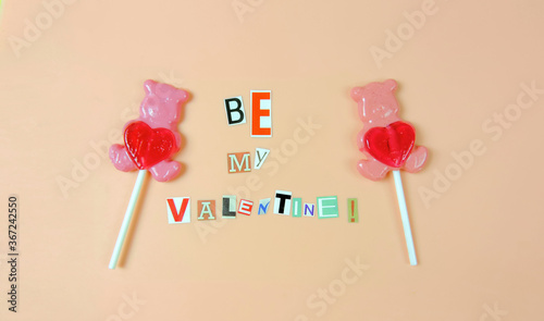 Be my Valentine - words from paper letters on a pink background and lollipops pink bears with heart, love concept 