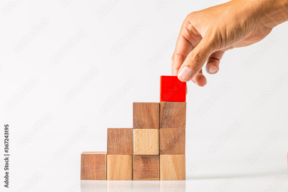 hand adding the last missing wooden block into place. Business success concept. hand adding the last missing wooden block into place. Business success concept.