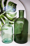 Two green glass bottles with leaf background decor