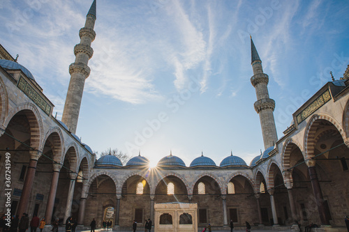 Istanbul, Turkey - December 2018: View on Suleymaniye Mosque with people inside yard with beautiful sun light and minarets on blue sky