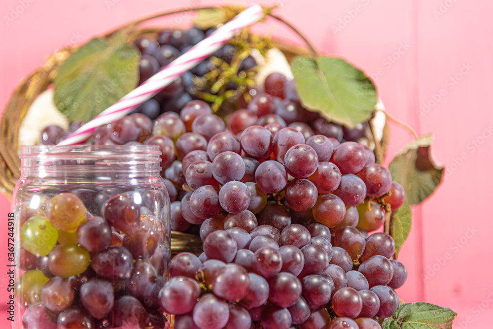 Bunches and grains of the Vitis vinifera variety on pink background