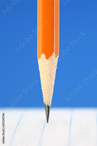 Number 2 yellow pencil with sharp pencil tip on lined paper. New school supplies.
