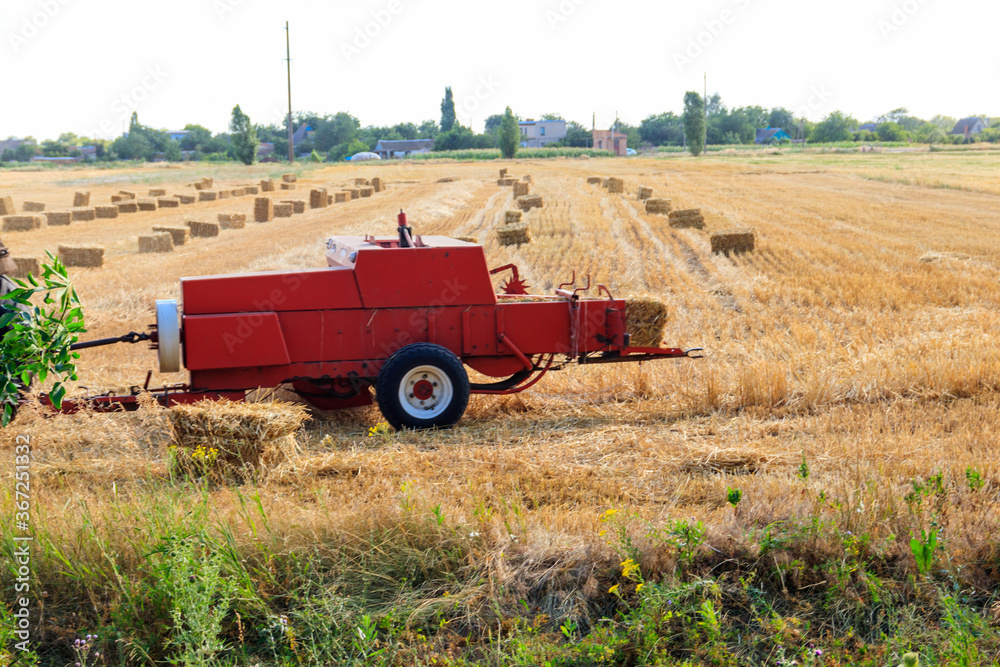 Rectangular baler discharges a straw bale in a field during the harvesting process Rectangular baler discharges a straw bale in a field during the harvesting process
