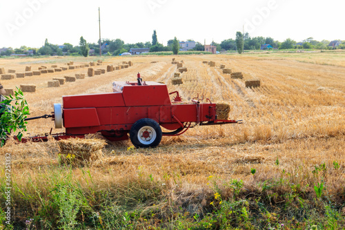 Rectangular baler discharges a straw bale in a field during the harvesting process