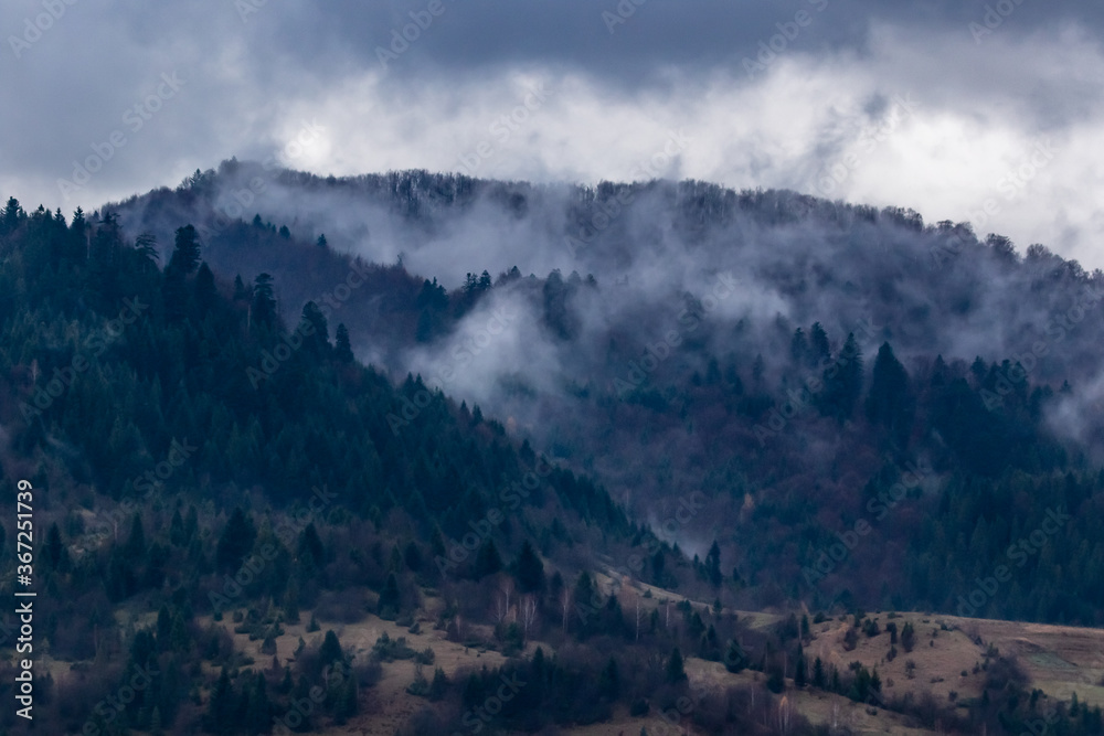 The tops of high mountains are hidden by clouds. Fog. Autumn landscape. Panoramic view.