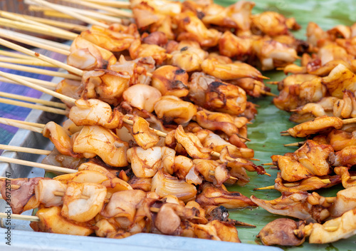 Squid skewers waiting to be grilled in charcoal grill. Thai delicious street food in local market.