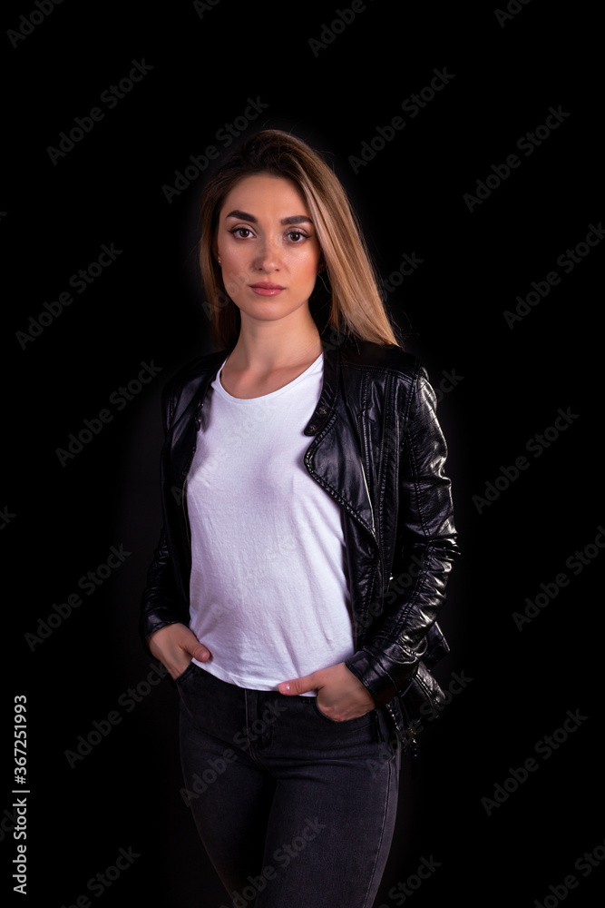A young girl in a black leather jacket isolated on a black background A young girl in a black leather jacket isolated on a black background