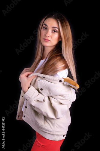 A young girl in a jacket and red trousers isolated on a black background