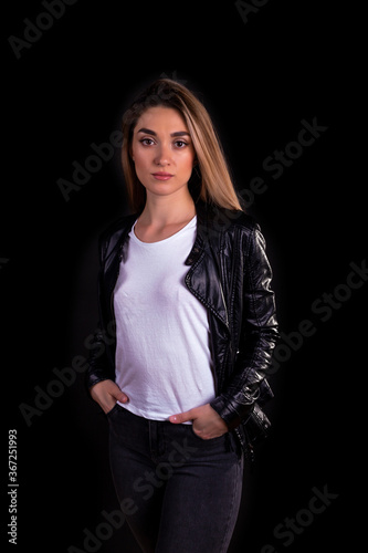 A young girl in a black leather jacket isolated on a black background
