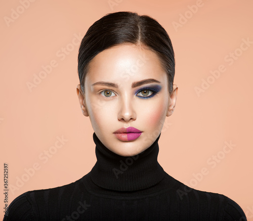 One half face of a beautiful white woman with  bright makeup and the other is natural. Woman portrait with a deep blue eye makeup of one eye. Natural and  vivid make-up on a female face. Fashion style