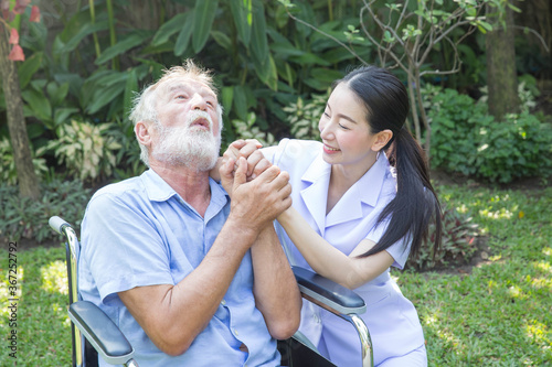 A nurse take care a senior male on wheelchair in his garden at home © PinkBlue