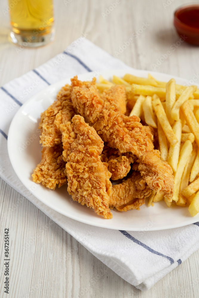 Homemade Crispy Chicken Tenders and French Fries with sauce and glass of cold beer, low angle view. Homemade Crispy Chicken Tenders and French Fries with sauce and glass of cold beer, low angle view.