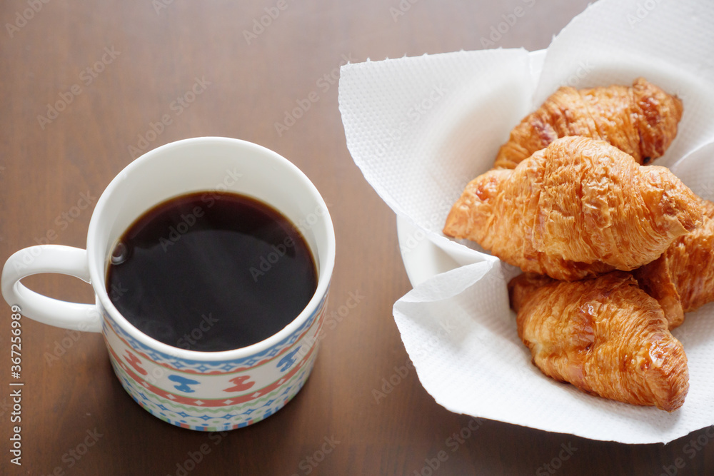 マグカップに入れたコーヒーと皿に入れたクロワッサン マグカップに入れたコーヒーと皿に入れたクロワッサン
